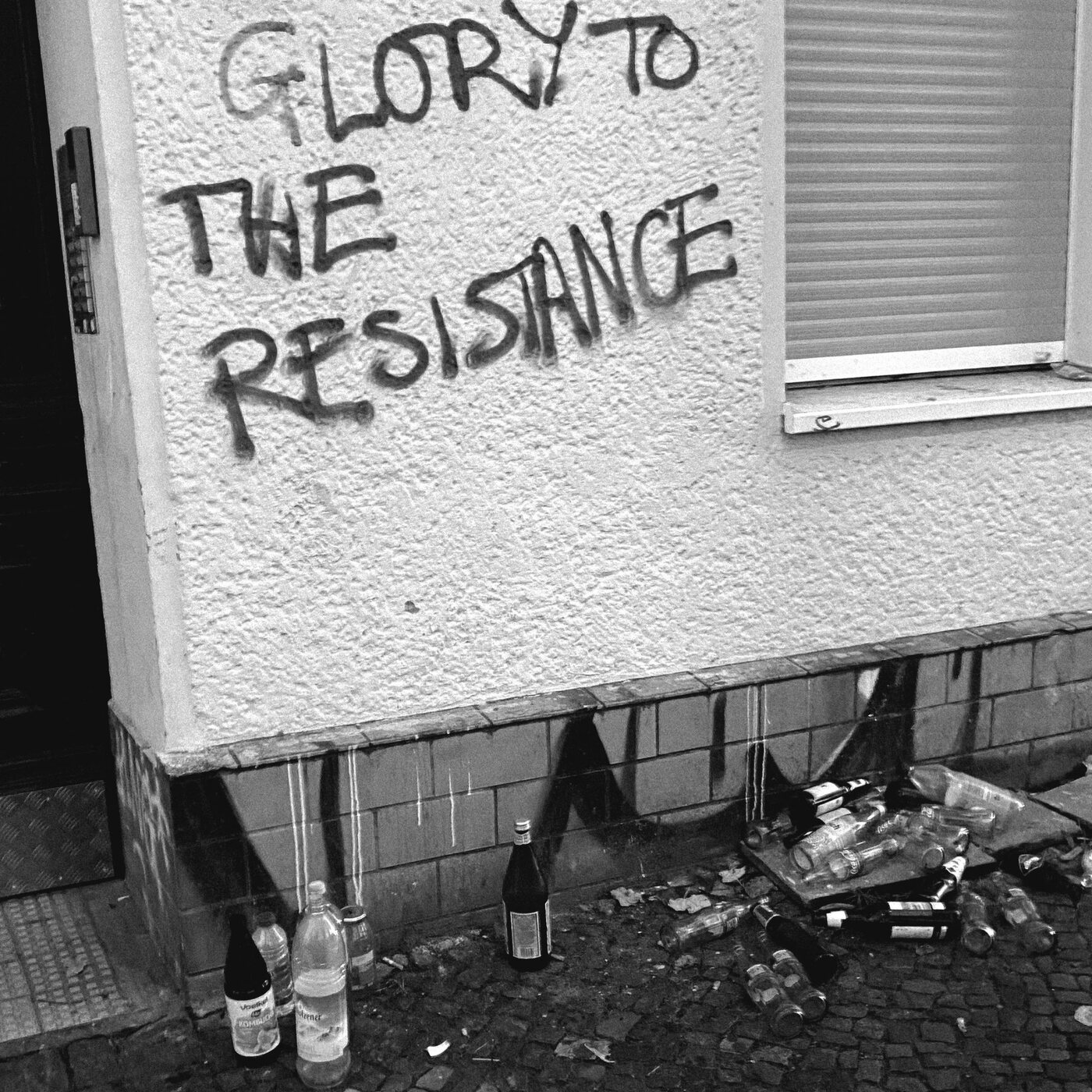 Graffiti reading Glory to the Resistance above discarded bottles