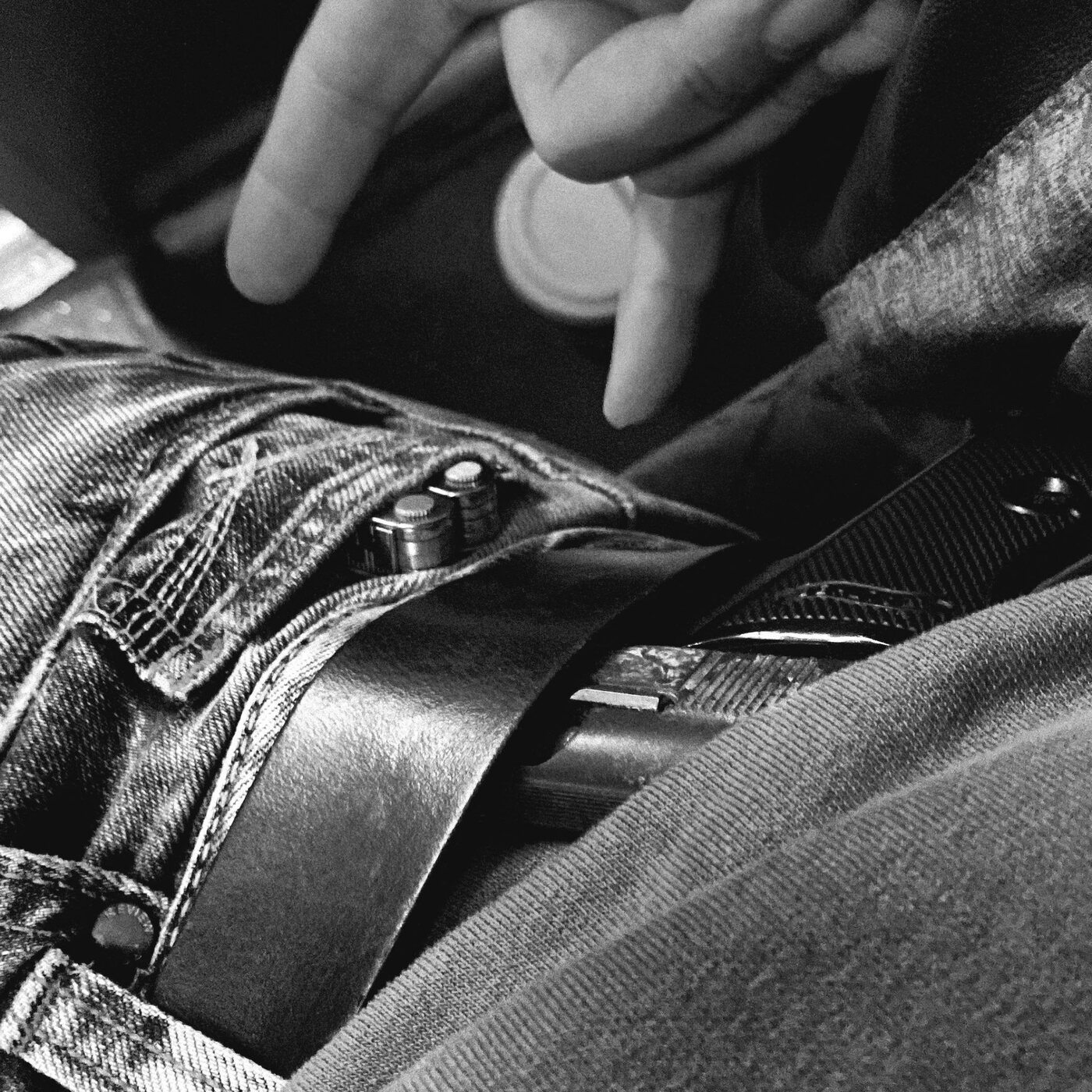 Close-up of hands, belt, and dark clothing